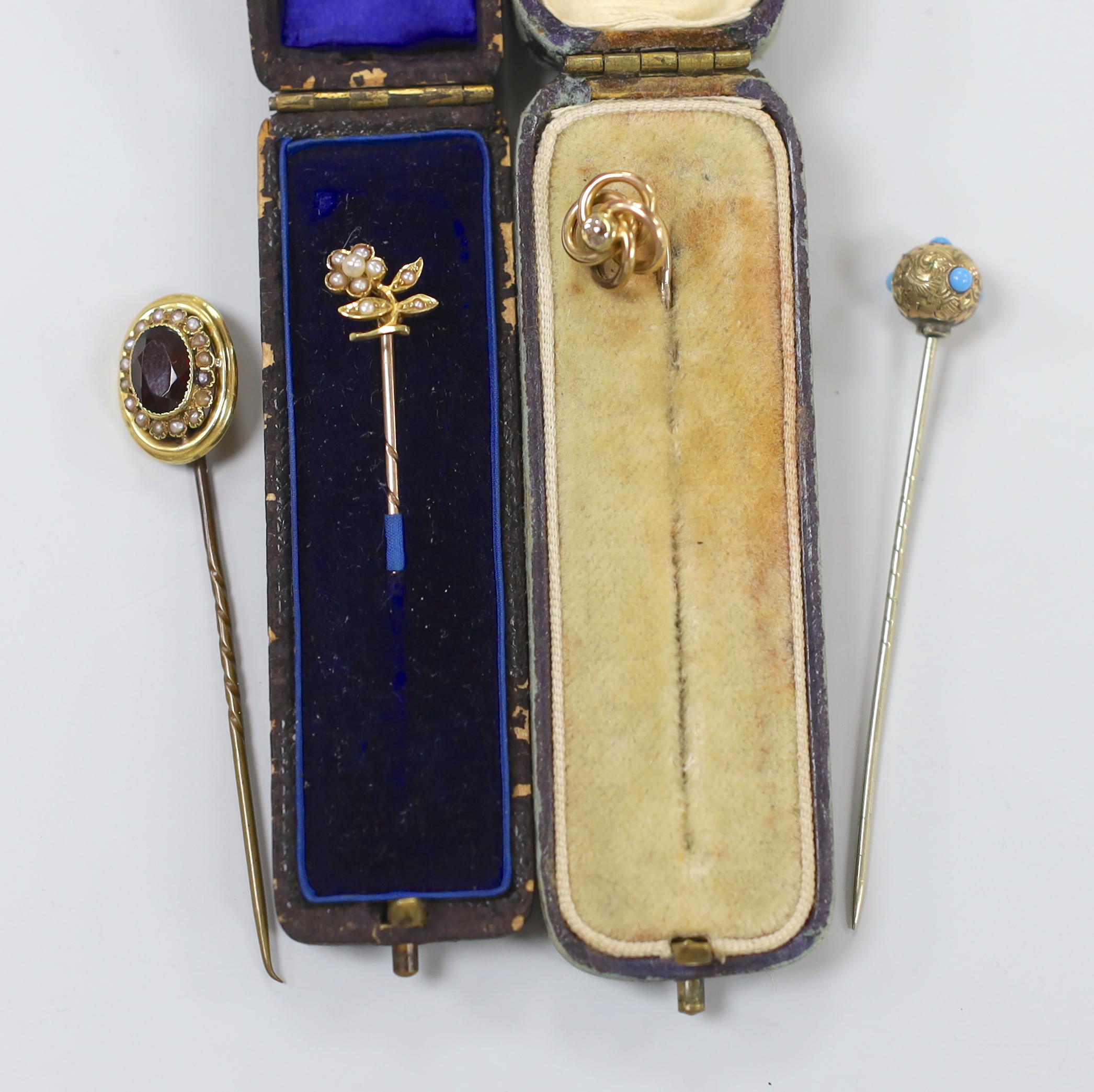 Four assorted late Victorian yellow metal and gem set stick pins, including diamond set and garnet and seed pearl cluster, largest 68mm.